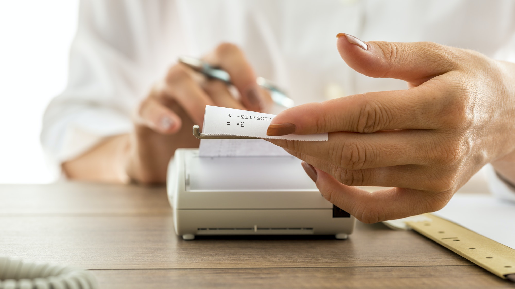 Woman holding a printout receipt as it comes out of adding machine