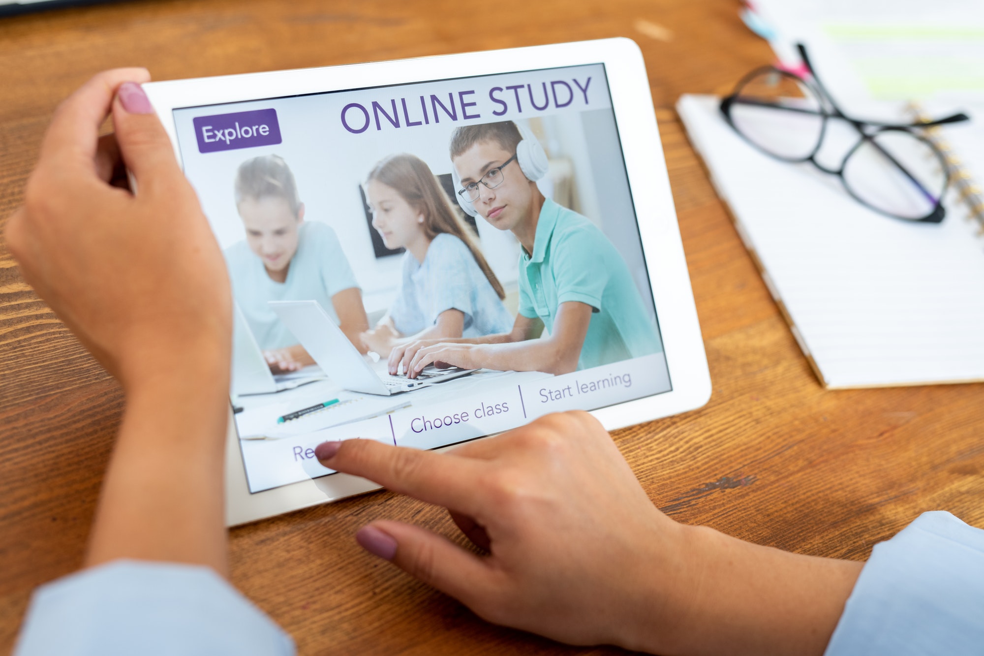 Woman pressing button on touchpad display to register on educational website